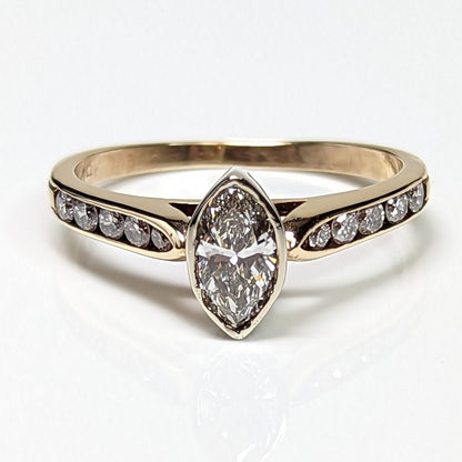 Gold ring with a marquise-shaped diamond and smaller diamonds on a white background