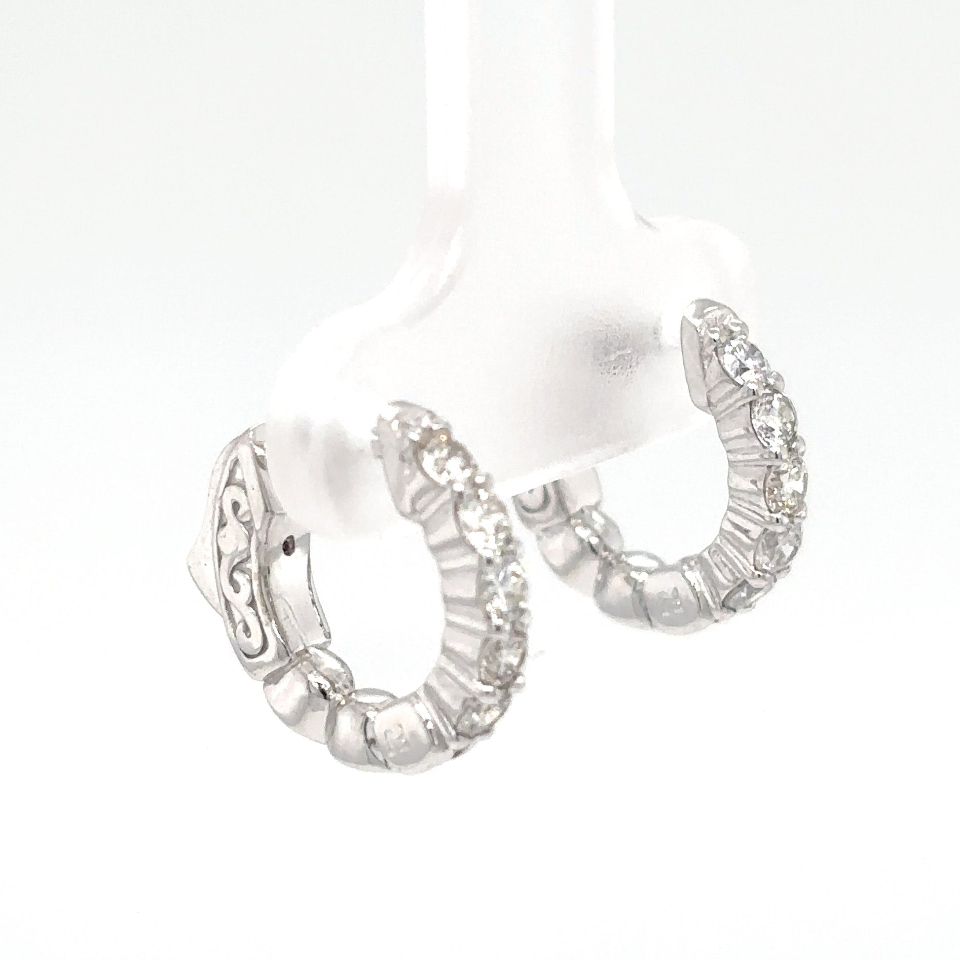 Silver hoop earrings with intricate designs on a white background