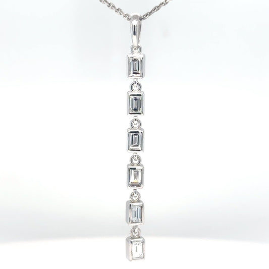 Close-up of a 14K white gold pendant with bezel-set baguette diamonds in a vertical line, suspended from a fine white gold chain.
