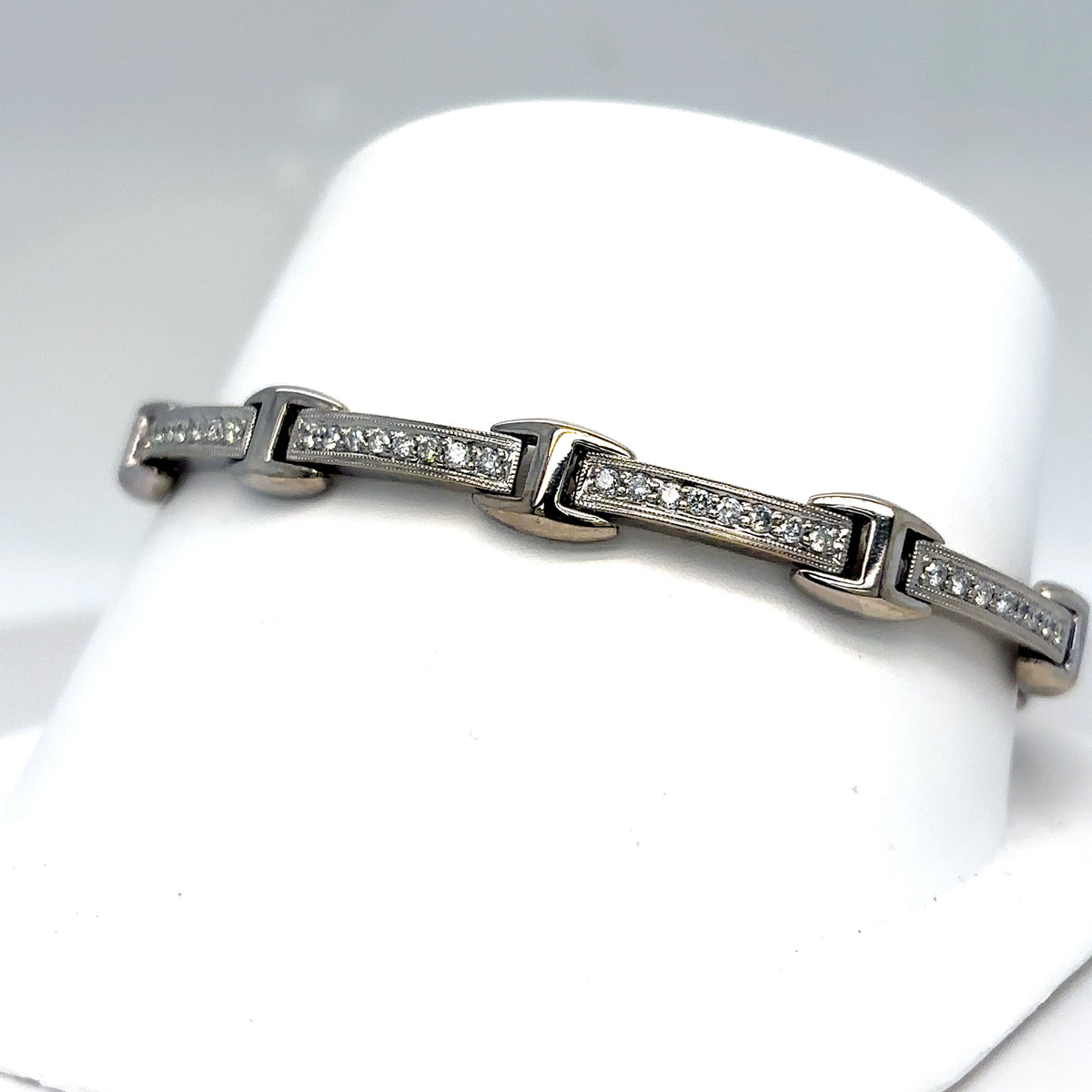 Silver bracelet with embedded diamonds on a white stand