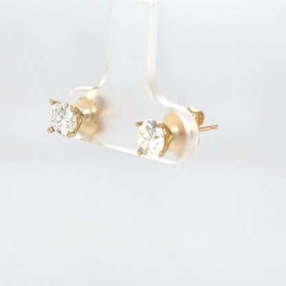 Gold stud earrings with clear gemstones on a light gray background