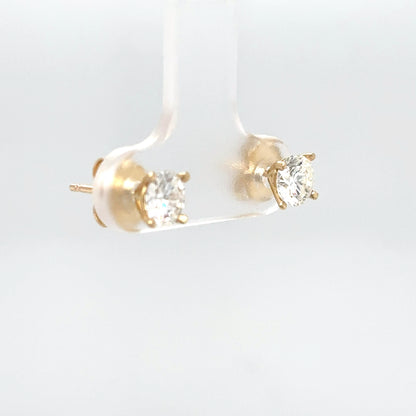 Gold stud earrings with clear gemstones on a light gray background
