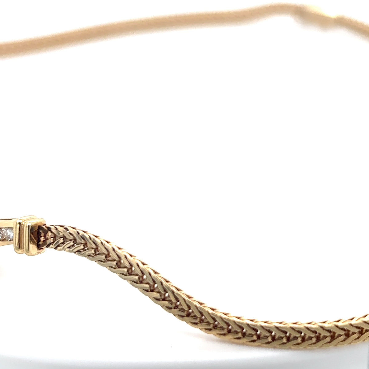 Gold bracelet with braided design on a white background