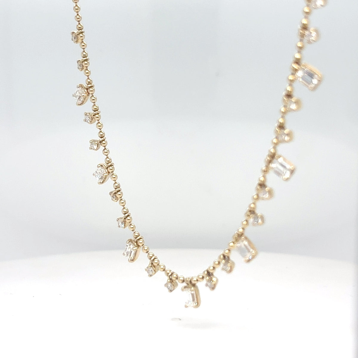 A delicate 14K yellow gold chain necklace set with emerald-cut and round brilliant diamonds, displayed against a white background.