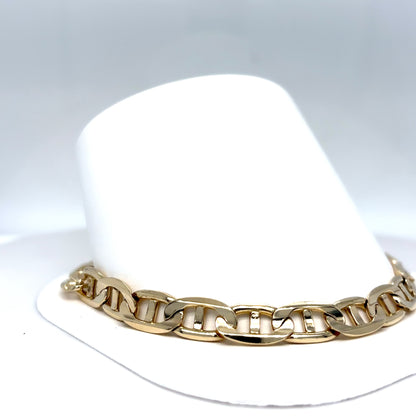 Gold chain bracelet on a white hat with a light gray background
