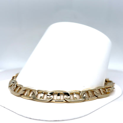 Gold chain bracelet on a white hat with a gray background