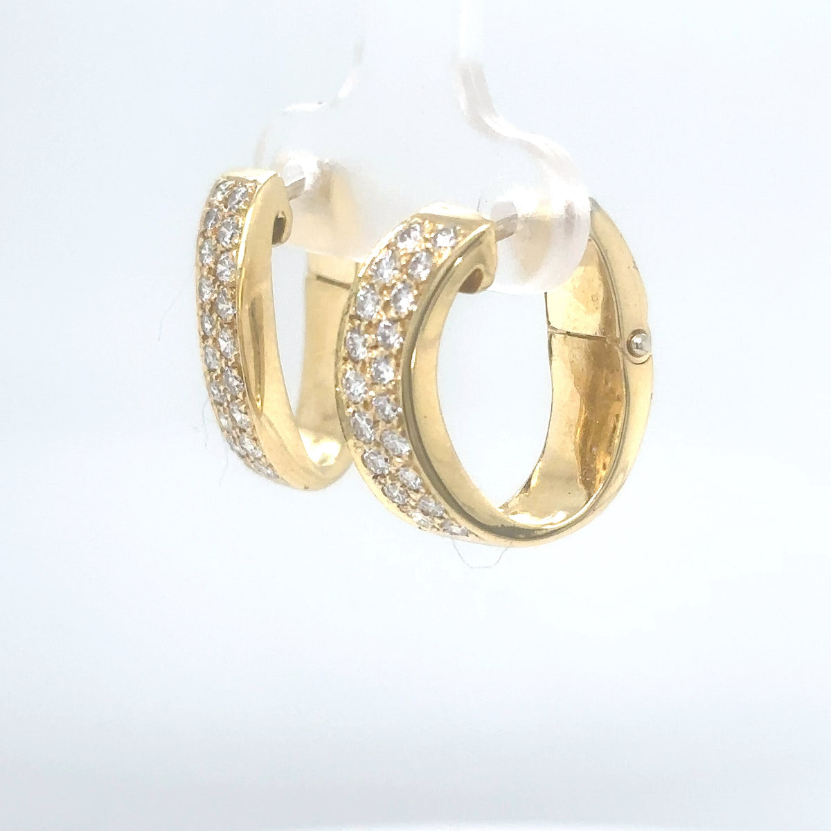 Gold hoop earrings with clear gemstones on a light gray background