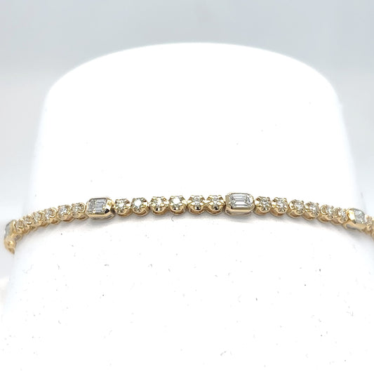 An 18K yellow gold tennis bracelet set with emerald-cut and round brilliant diamonds, displayed on a white cylindrical stand against a light gray background.